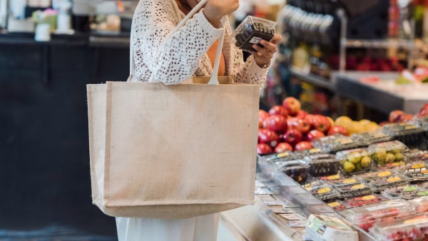Persoon met een herbruikbare tas bekijkt een product in de winkel