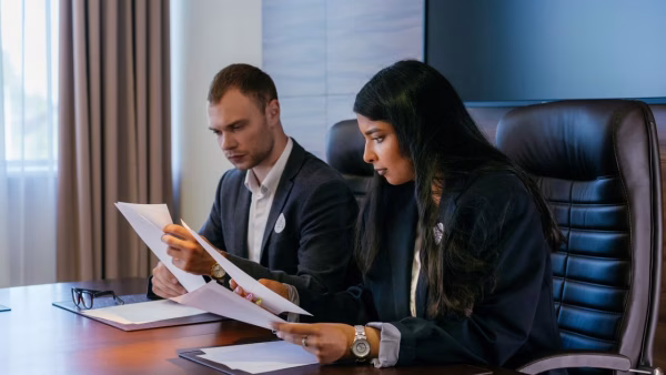 Twee collega's bekijken samen documenten aan een kantoortafel