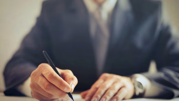 Close-up van een man die een document ondertekent aan een bureau