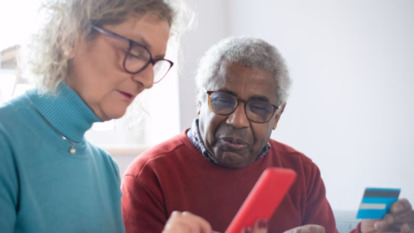 Ouder echtpaar bekijkt samen een betaalpas en telefoon