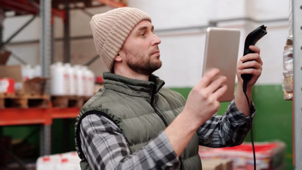 Magazijnmedewerker scant voorraad met een handscanner en tablet
