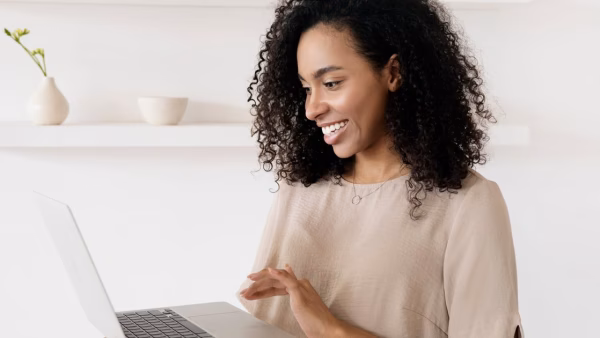 Lachende vrouw kijkt naar laptop in een lichte kamer