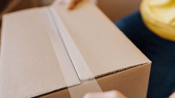 Man verzegelt een verzenddoos met tape
