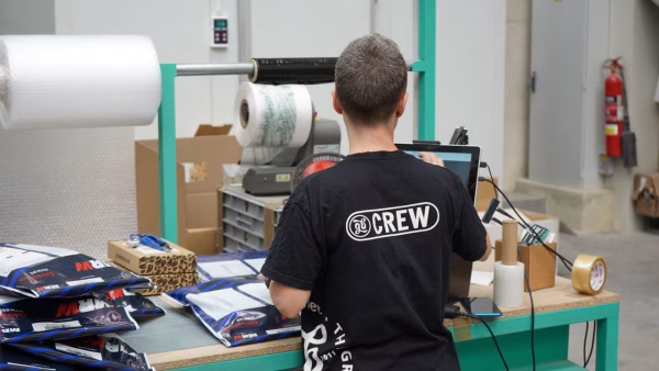 Magazijnmedewerker controleert voorraad met een computer tussen de dozen