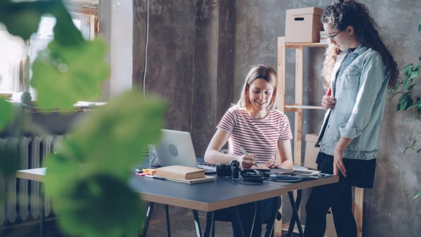 Twee vrouwen overleggen samen aan een bureau in een klein bedrijf