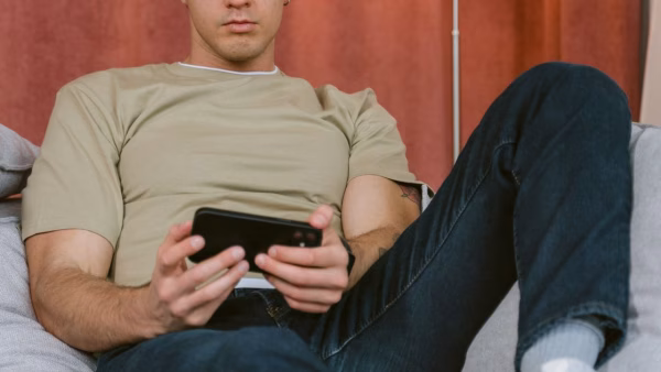 Man op de bank kijkt naar zijn telefoon terwijl hij een oproep krijgt