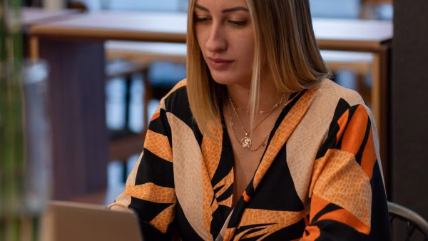 Vrouw bekijkt producten op haar laptop in een koffiezaak
