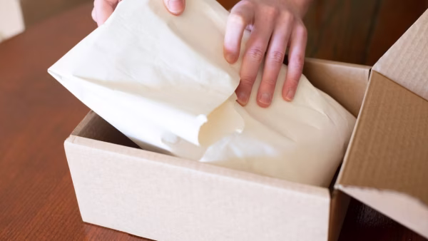 Iemand pakt voorzichtig een bestelling in met beschermend papier