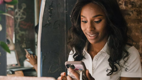 Lachende vrouw rondt op haar smartphone een online betaling af in een café