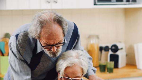 Ouder echtpaar bekijkt samen garantiepapieren aan de keukentafel