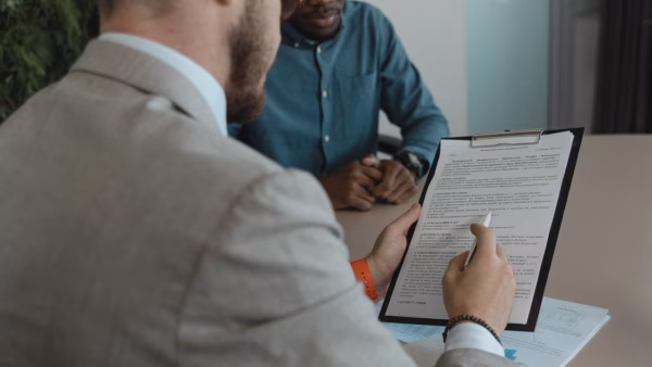 Twee collega's bekijken samen een contract op een klembord op kantoor