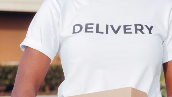 Close-up van een bezorger met een shirt met opdruk Delivery die een pakket vasthoudt