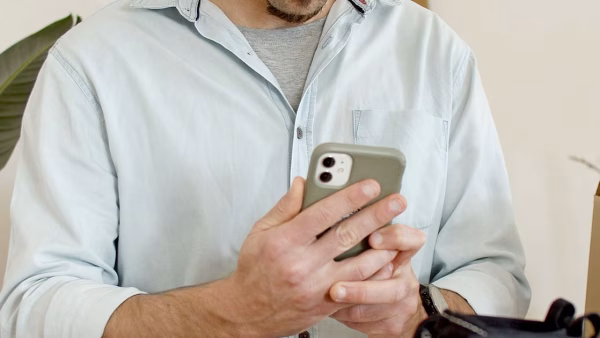 Man maakt met zijn smartphone een productfoto van schoenen naast een verzenddoos