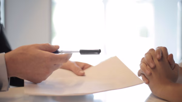 Ondernemer ondertekent een contract met algemene voorwaarden tijdens een gesprek op kantoor