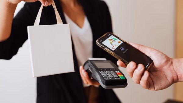 Klant betaalt contactloos met smartphone bij een betaalterminal in een winkel