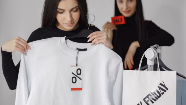 Twee vrouwen bekijken een kortingslabel op een trui tijdens het winkelen