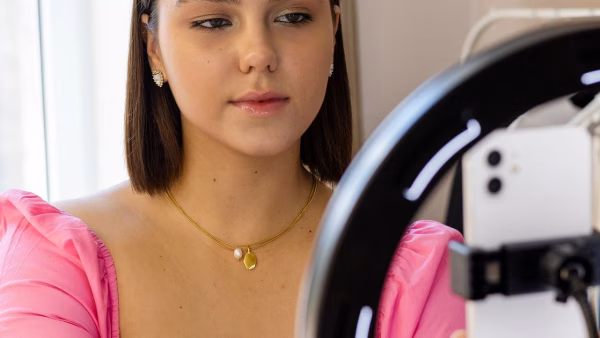Jonge vrouw neemt contentvideo op met haar telefoon en een ringlamp